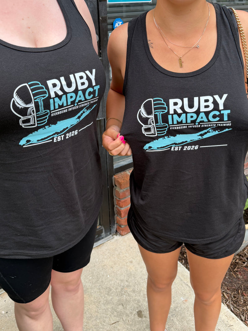 Two women wearing matching black tank tops with a 'RUBY IMPACT EST 2026' graphic, standing outdoors on a sidewalk.